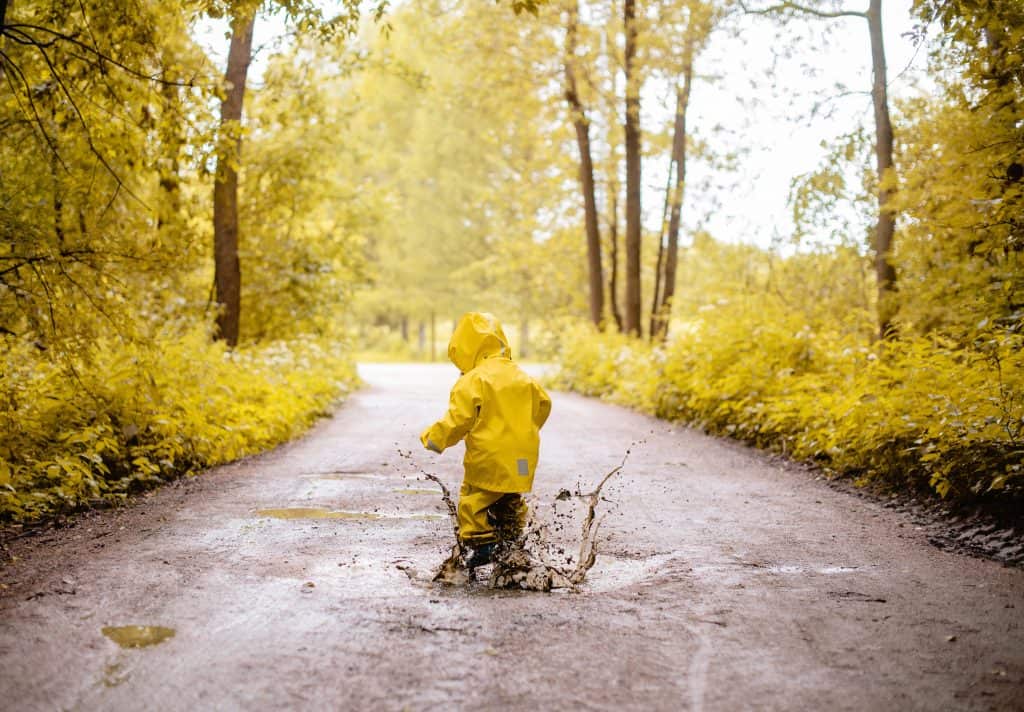Girl jumping in puddles in non-toxic rain gear