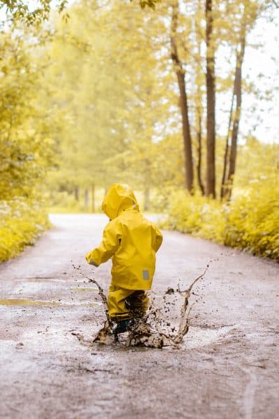 Girl jumping in puddles in non-toxic rain gear