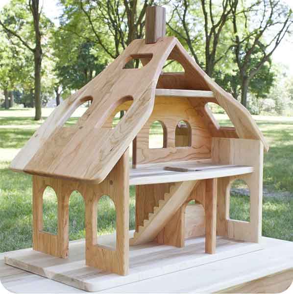 Wooden dollhouse on a table with foliage in the background