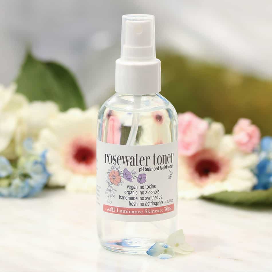 Rosewater toner on a table with flowers in the background