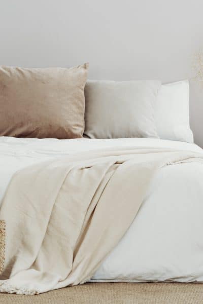 White and beige organic sheets on double bed in simple interior