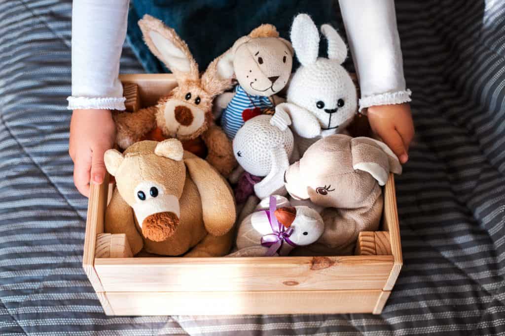 child holding wood box with organic stuffed animals. 