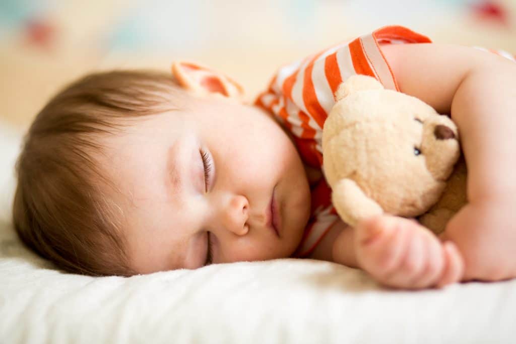 infant baby sleeping with plush organic stuffed animal