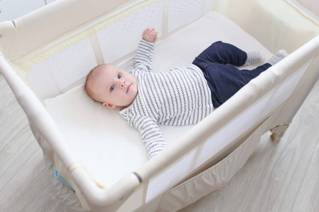 3 month old girl lying in non-toxic travel crib