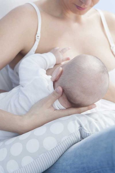 woman breastfeeding baby on organic breastfeeding pillow
