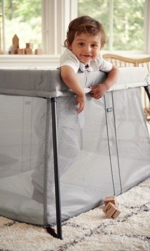 boy standing up inside of a non-toxic travel crib
