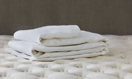 two organic waterproof mattress protectors sitting on top of a mattress. 