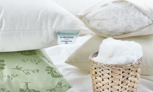 White Lotus Home organic pillows stacked on top of each other with a basket of organic cotton