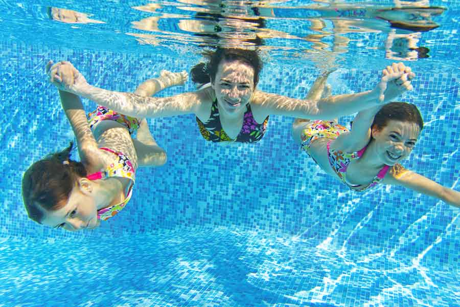 Woman and 2 kids swimming in pool underwater smiling for the camera