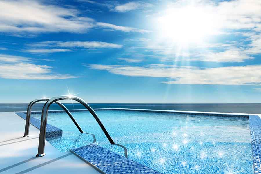 Empty swimming pool filled with water with sun and clouds in the background, using ways to naturally protect from chlorine in swimming pools. 