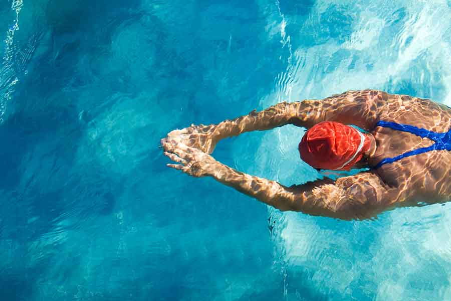 Swimmer from above with a swim cap in the water and goggles to naturally protect from chlorine in swimming pools
