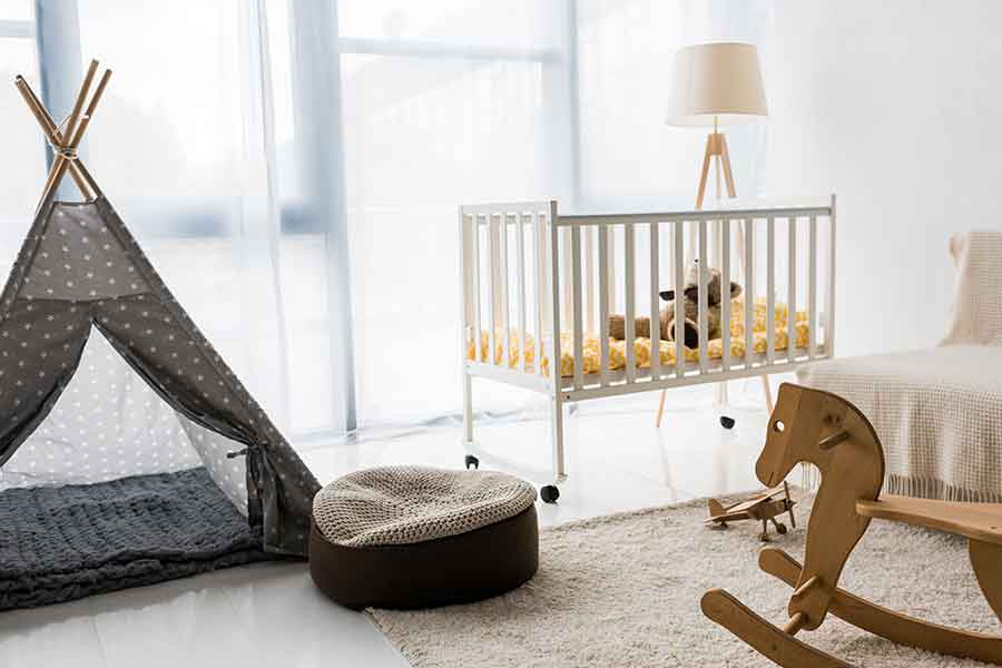 Baby nursery with a tent, crib, wooden rocking horse, and bright open windows