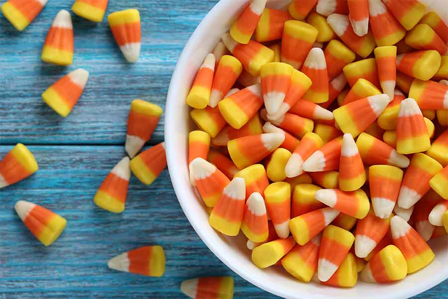Candy Corn in a white bowl on blue wooden table