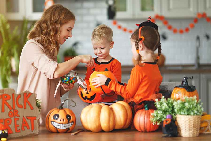 A mother giving candy and celebrating Halloween with her 2 kids